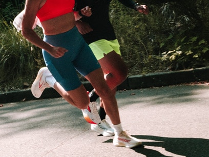 Two people running on a sidewalk