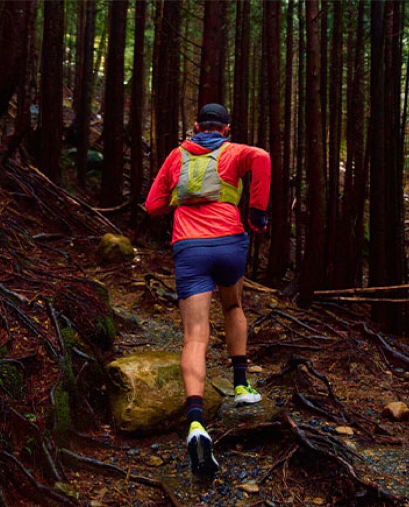 Model running in a forest with Brooks trail gear