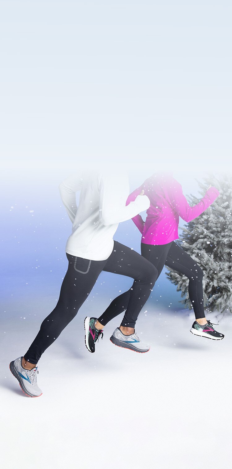 Two people running with snow falling