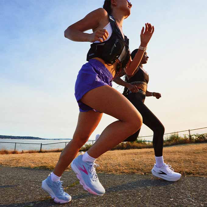 Two women run outside on a sunny day