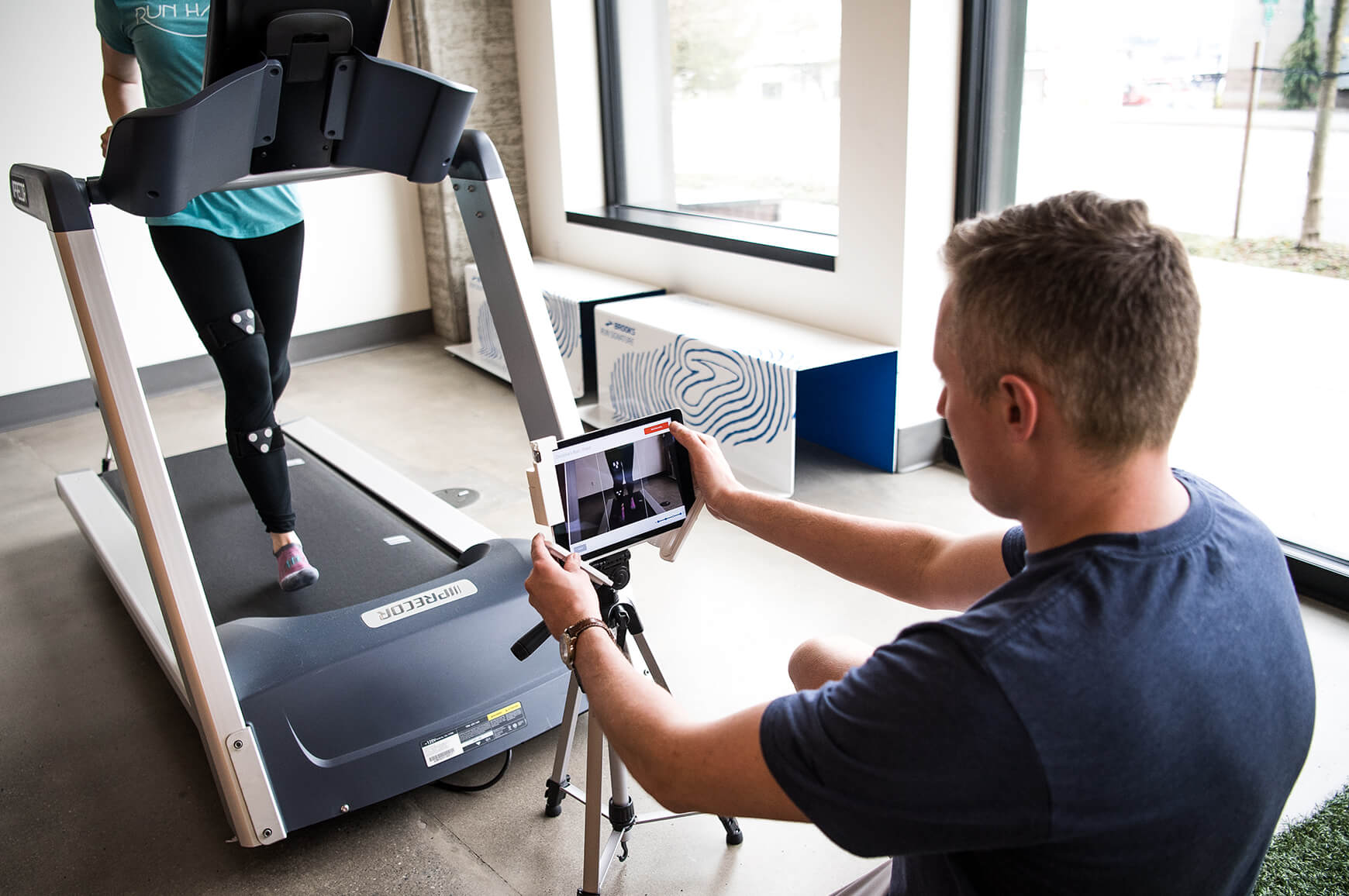 A Brooks employee analyzing a runner's gait on a treadmill