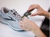 A person works on a Brooks shoe