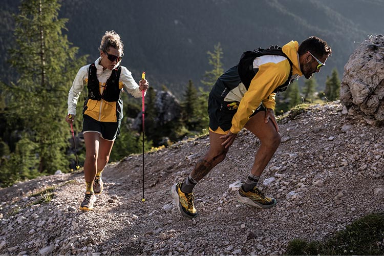 Two trail runners ascend a rocky hillside