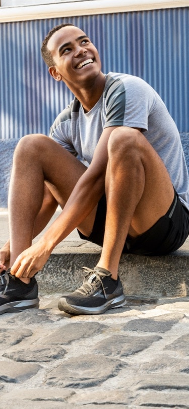 Man sitting on a step tying his shoes