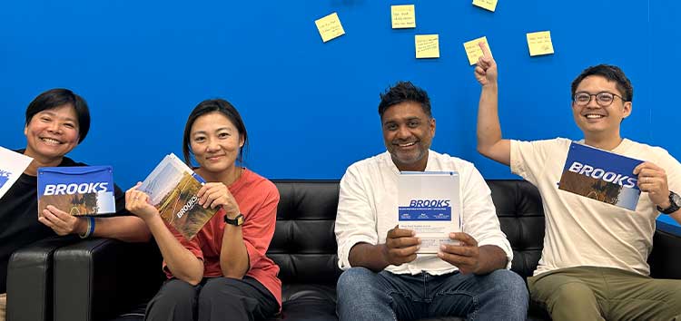 Four people sitting on a couch, holding Brooks notebooks