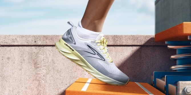 Side view of a grey and yellow running shoe on an orange step